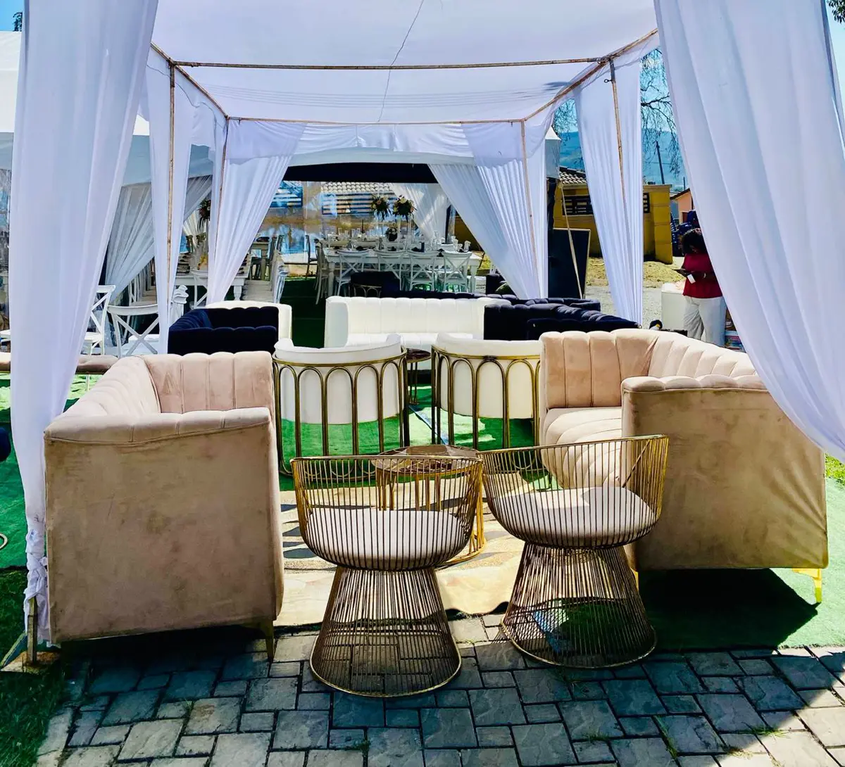 Outdoor lounge seating beneath a white draped canopy at an event